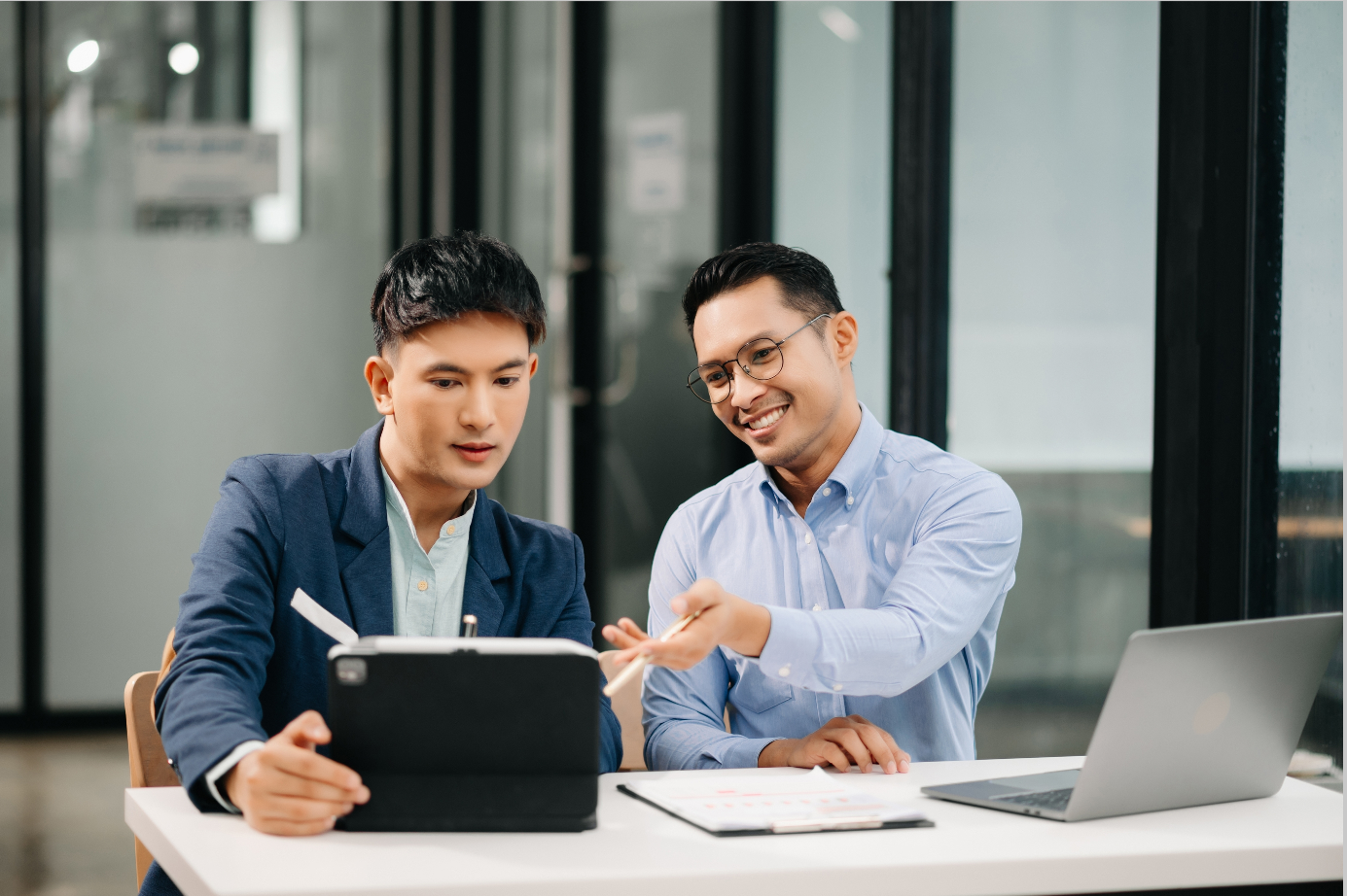 Two men sitting at table reviewing a document.